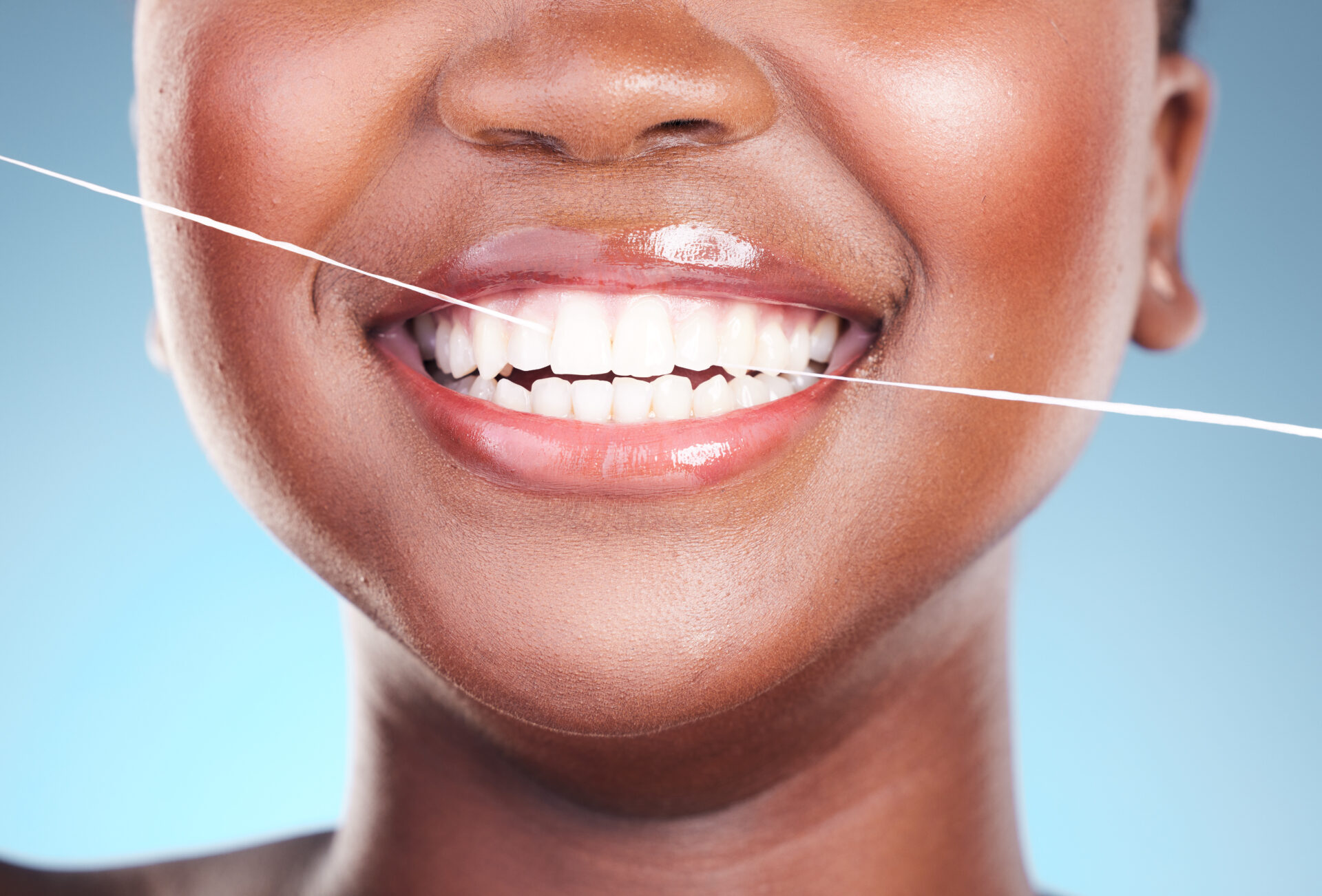 Happy woman, teeth and dental floss in cleaning, hygiene or cosmetics against a blue studio backgro.